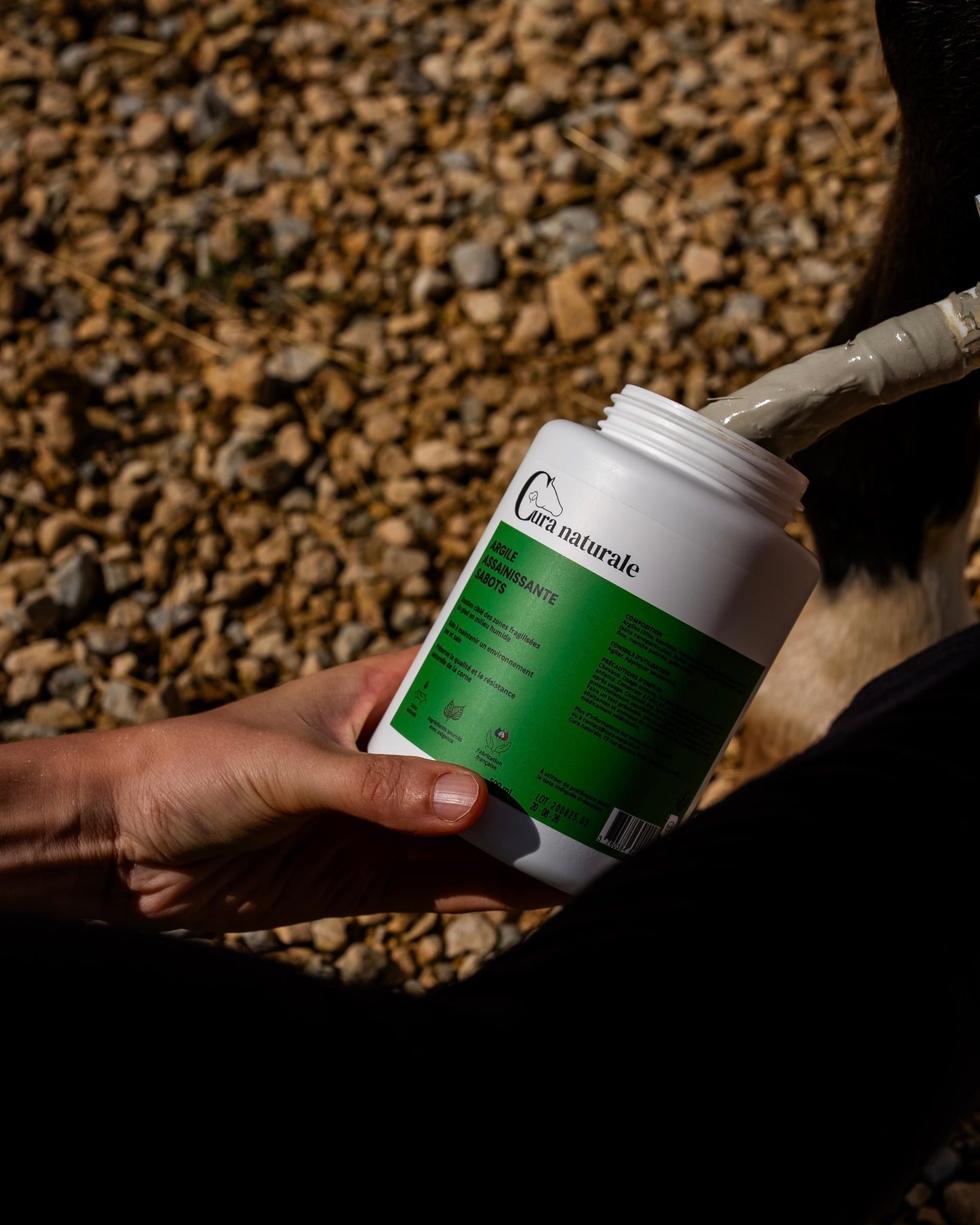 Pot d’argile assainissante sabots Cura Naturale tenu en main en extérieur