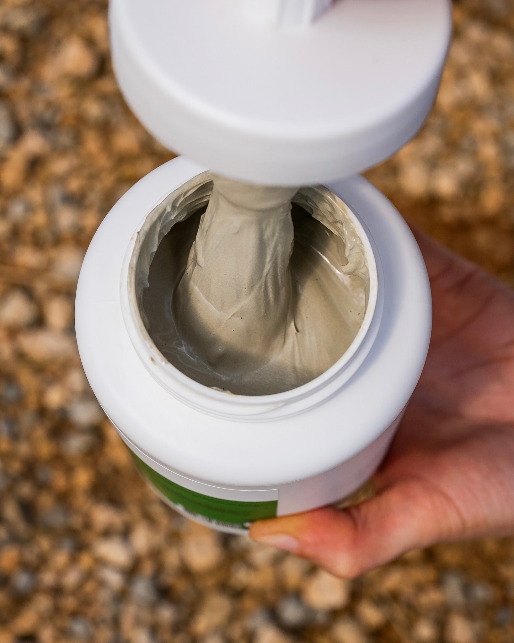 Pot d’argile assainissante sabots Cura Naturale tenu en main, texture visible